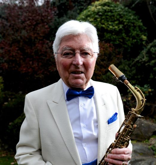 Stan holiding his saxophone, looking smart in a jacket and bow tie