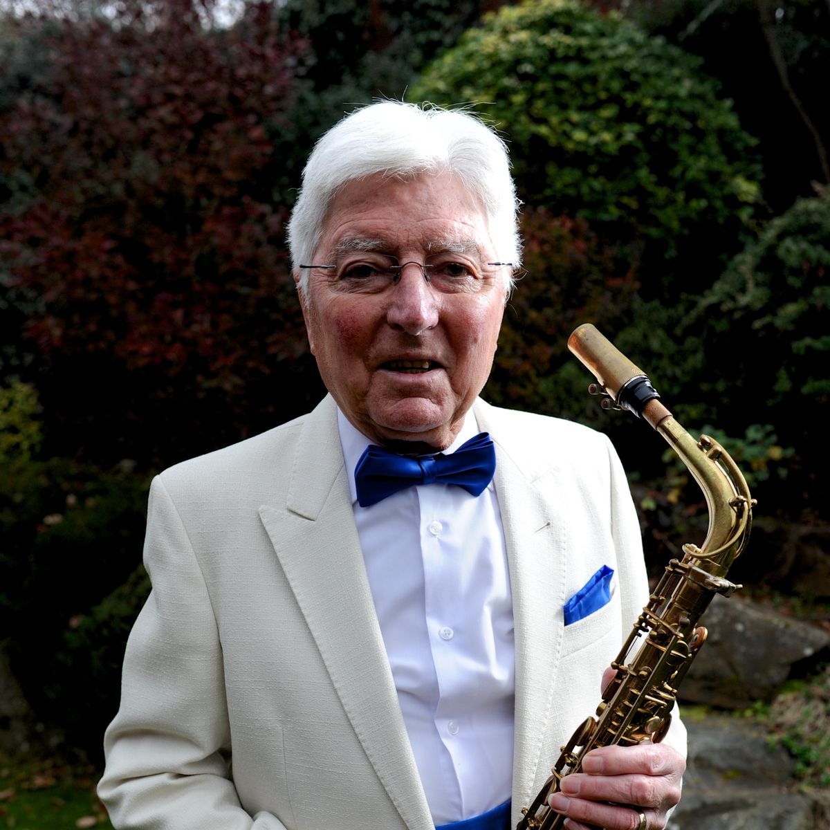 Stan holiding his saxophone, looking smart in a jacket and bow tie